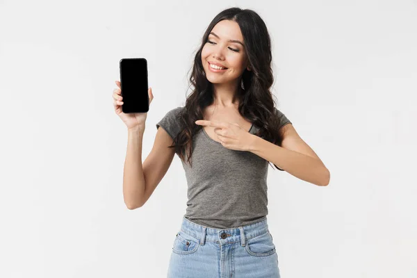 Красива збуджена щаслива молода жінка позує ізольовано на білому тлі стіни, показуючи відображення мобільного телефону . — стокове фото