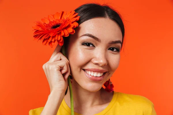 Krásná šťastná mladá žena pózovaná přes oranžovou stěnu na pozadí květinové květiny. — Stock fotografie