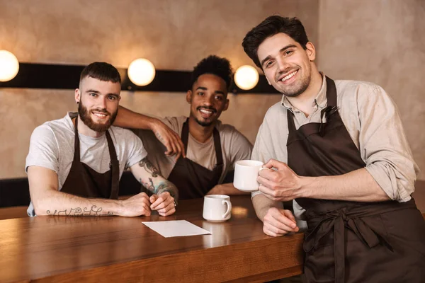 Tre allegri baristi uomini alla caffetteria — Foto Stock