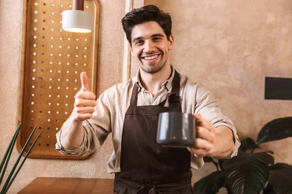 Mutlu genç adam barista önlük giyiyor