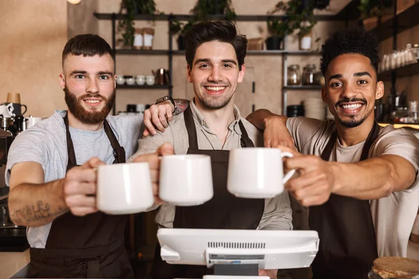 Grupo de homens alegres baristas vestindo aventais — Fotografia de Stock