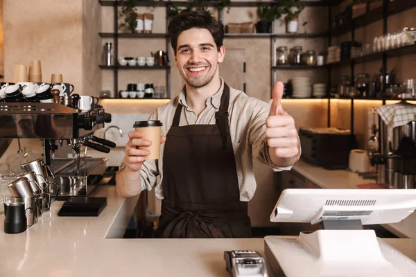 Handsome happy coffee man posing in cafe bar working indoors holding coffee cup.