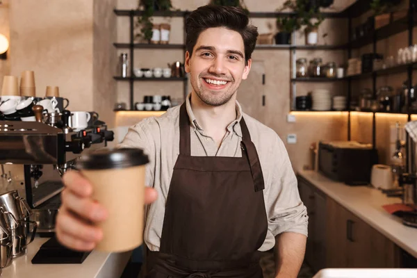 Bonito homem de café feliz posando em bar de café trabalhando dentro de casa segurando xícara de café . — Fotografia de Stock