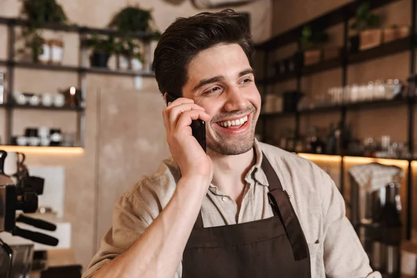 Handsome happy coffee man posing in cafe bar working indoors talking by mobile phone. — Stock Photo, Image