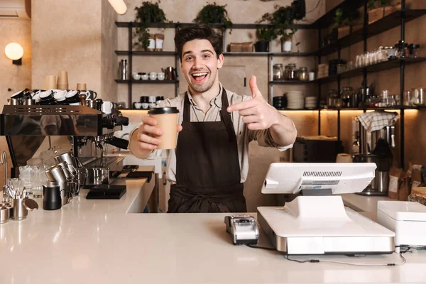 Bonito homem de café feliz posando em bar de café trabalhando dentro de casa segurando xícara de café . — Fotografia de Stock