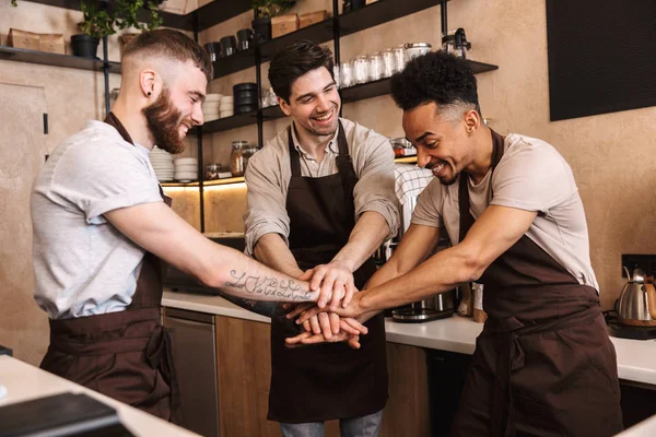 Grupo de homens alegres baristas vestindo aventais — Fotografia de Stock