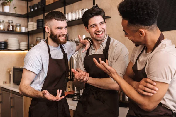 Grupo de homens alegres baristas vestindo aventais — Fotografia de Stock
