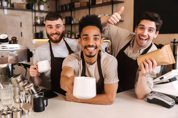 Group of cheerful men baristas wearing aprons — Stock Photo, Image