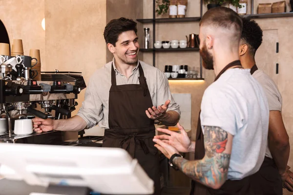 तीन खुश पुरुष बारिस्ट कॉफी की दुकान पर खड़े — स्टॉक फ़ोटो, इमेज