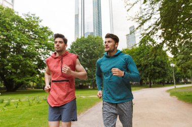 İki atletik yakışıklı erkek egzersiz yapıyor ve şehir parkı çalışan Fotoğraf