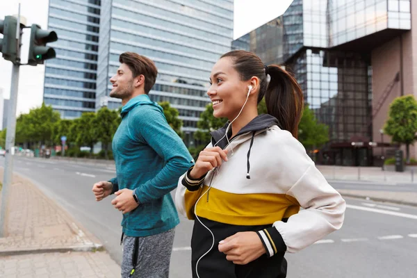 Foto de gente atlética sonriendo haciendo ejercicio y corriendo en la calle de la ciudad — Foto de Stock