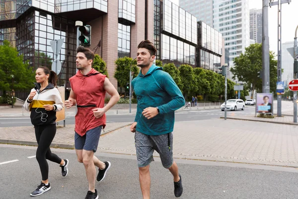 Photo of athletic strong people doing workout and running on city street