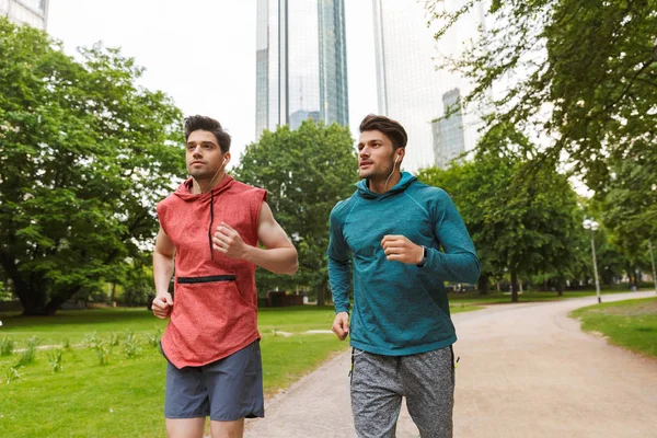 İki atletik yakışıklı erkek egzersiz yapıyor ve şehir parkı çalışan Fotoğraf