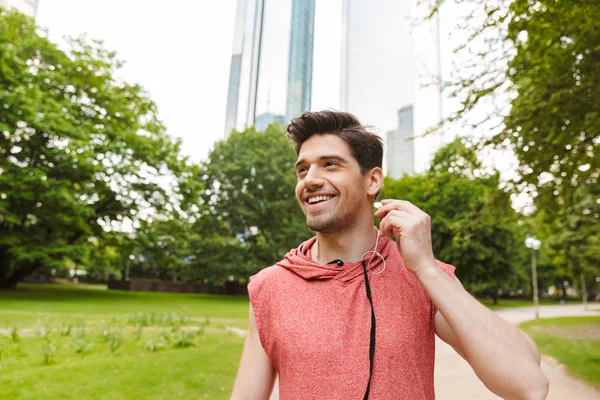Fénykép-ból mosolygó ember hallgató zene-val fülhallgató rövid idő működő ki-ban város Park — Stock Fotó