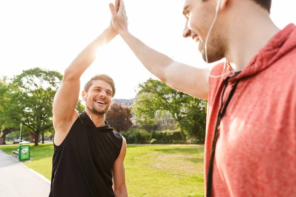İki mutlu yakışıklı erkek fotoğraf egzersiz yapıyor ve şehir parkı çalışan