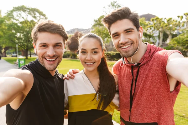 Foto de gente linda y feliz sonriendo y abrazándose mientras hace ejercicio en el parque de la ciudad — Foto de Stock