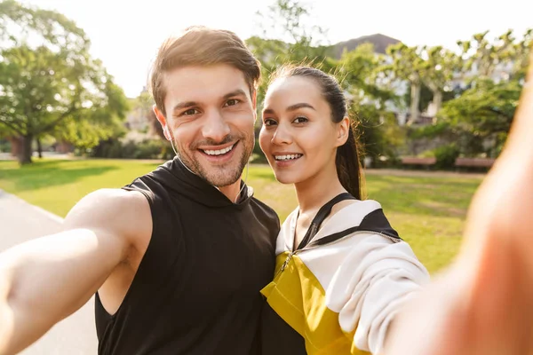 Fotó mosolyogva tetszett az ember és a nő vesz selfie fotó munka közben ki a városi parkban — Stock Fotó