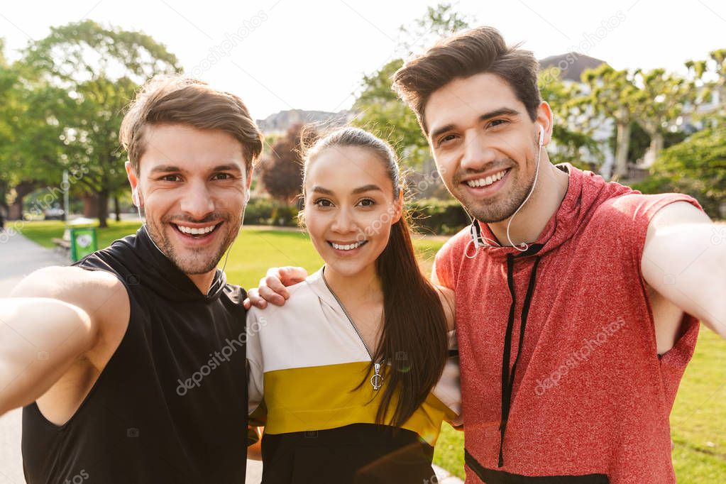 Photo of happy cute people smiling and hugging while working out in city park