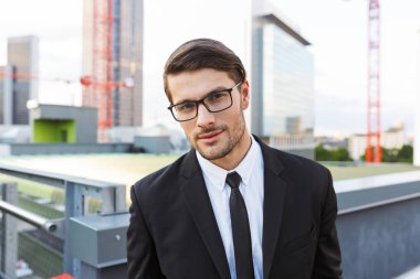 Açık havada yürüyen takım elbise giyen yakışıklı genç işadamı