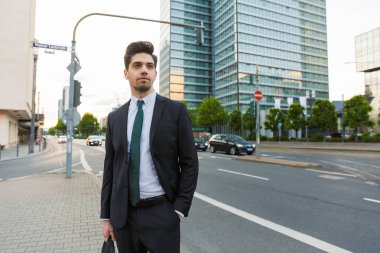 Açık havada yürüyen takım elbise giyen yakışıklı genç işadamı