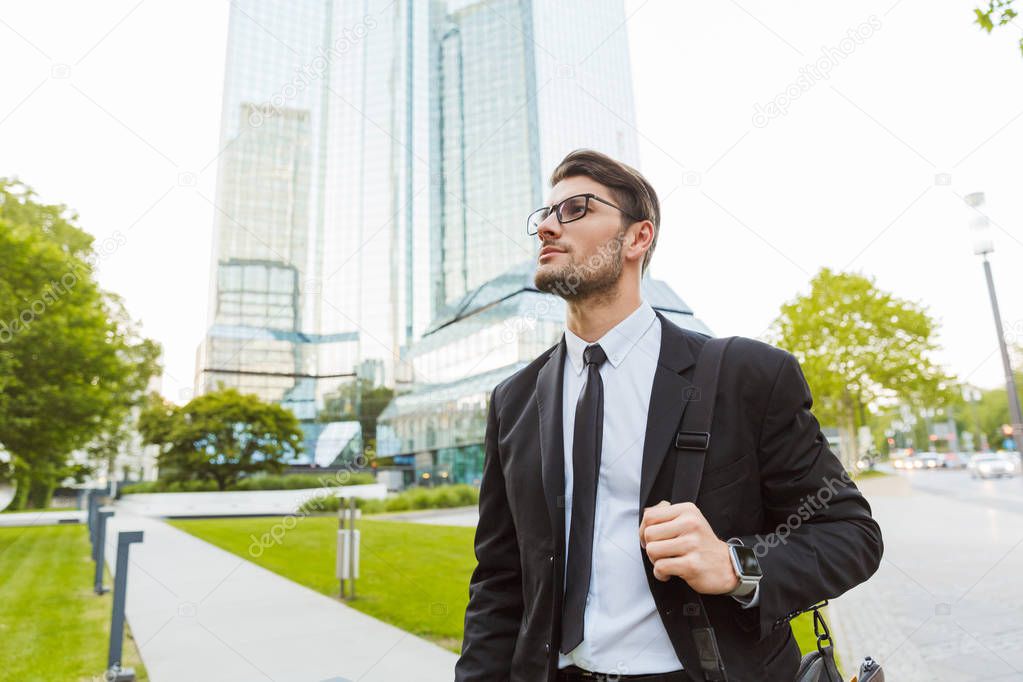 Handsome young businessman wearing suit walking outdoors