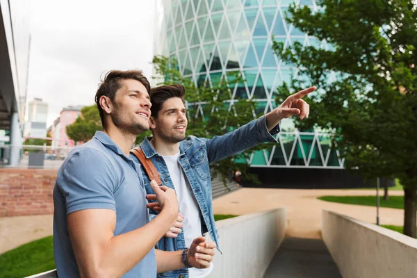 Two smiling young men friends dressed casually