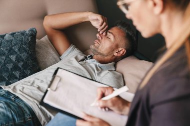 Beyaz adamın kanepeye yattığını ve odada psikologla sohbet edip konuşmalarını düşünme fotoğrafı