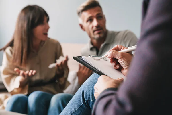 Foto de casal irritado intrigado ter conversa com psicólogo em sessão de terapia no quarto — Fotografia de Stock