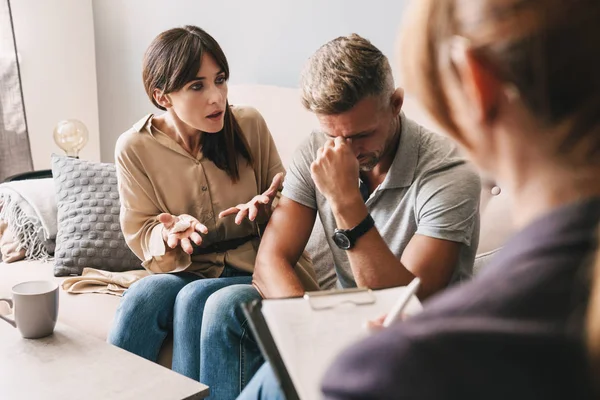 Photo of puzzled annoyed couple having conversation with psychologist on therapy session in room — Stock Fotó