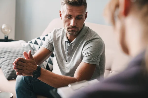 Foto van broeden ongeschoren man met een gesprek met psycholoog in de kamer — Stockfoto