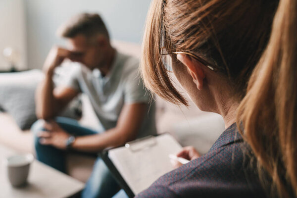 Photo of upset handsome man having conversation with psychologist in room