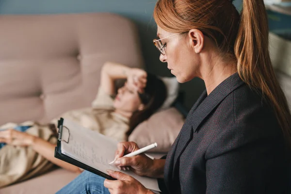 Photo of thoughtful caucasian woman having conversation with psychologist in room — Stock Photo, Image