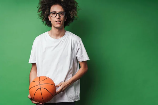 Portrait of serious caucasian man with afro hairstyle holding basketball and looking at camera — Stok Foto