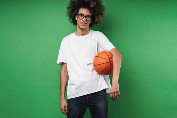 Portrait of young caucasian man with afro hairstyle holding basketball and looking at camera — Stok Foto