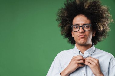 Kıvırcık adam resmi beyaz gömlek giymiş yeşil duvar arka plan üzerinde izole poz.