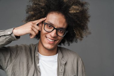 Kıvırcık mutlu neşeli genç adam gri duvar arka plan üzerinde izole poz.