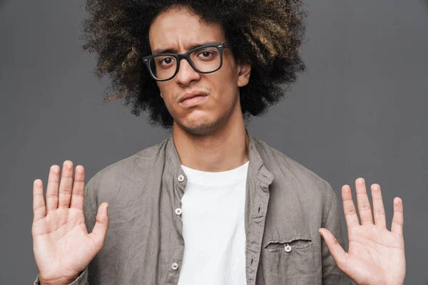 Sad displeased teenage guy posing isolated over grey wall background showing stop gesture. — Stock Photo, Image