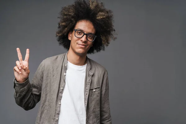 Foto van blij ongeschoren man met Afro kapsel eten en het tonen van vredesteken — Stockfoto