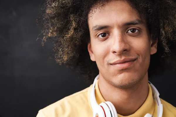 Curly jovem otimista positivo adolescente feliz posando sobre parede de quadro cinza com fones de ouvido . — Fotografia de Stock