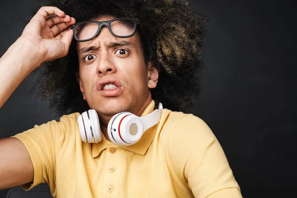 Bang tiener kerel poseren over grijs schoolbord muur met hoofdtelefoon dragen brillen. — Stockfoto