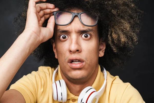 Наляканий хлопець-підліток позує над сірою стінкою крейди з навушниками в окулярах . — стокове фото