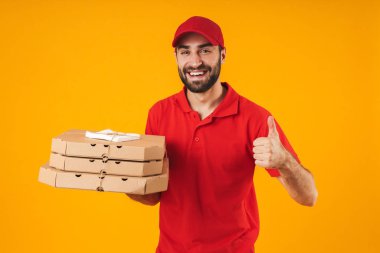 Kırmızı üniformalı traşsız teslimatçının portresi başparmağı nı gösteriyor