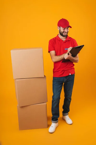 Retrato de homem de entrega alegre em vermelho uniforme segurando prancheta — Fotografia de Stock