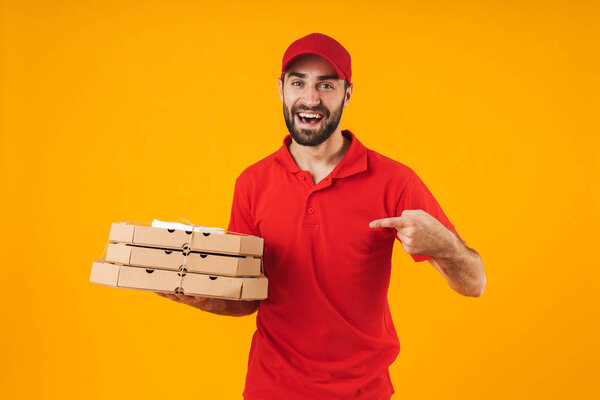 Portrait of attractive delivery man in red uniform smiling and h