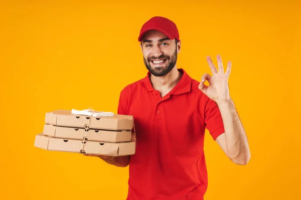 Retrato del repartidor positivo en uniforme rojo mostrando signo ok — Foto de Stock