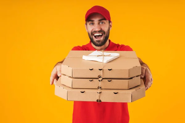 Portrait of handsome delivery man in red uniform smiling and hol — Stock Photo, Image