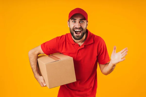 Retrato de homem de entrega animado em uniforme vermelho sorrindo e segurando — Fotografia de Stock