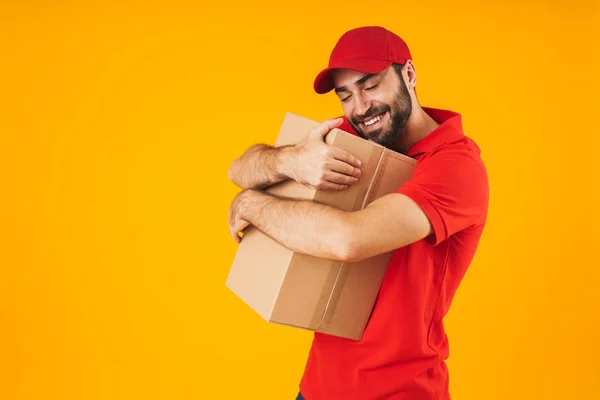 Image of young delivery man in red uniform smiling and hugging p