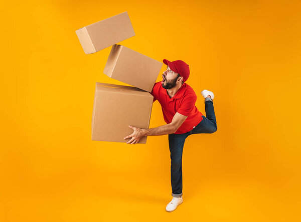 Full length portrait of shocked delivery man in red uniform carr