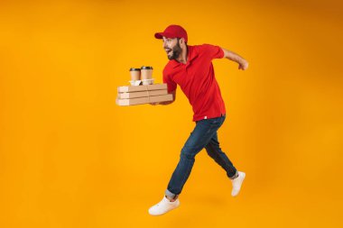 Pizza kutuları ve paket kahve ile çalışan kırmızı üniformalı genç teslimatçı portresi